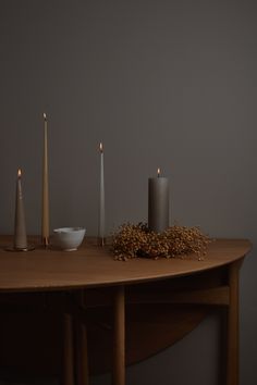 three candles are sitting on a table next to a bowl