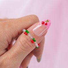 a woman's manicure with red and green berries on the tip of her nails