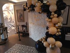 the balloon arch is decorated with black, white and gold balloons