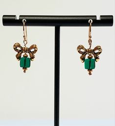 "- Adorable Christmas Presents Hook Earrings with Antique Gold Bow on top. See Photos #1-3. - Swarovski Faceted Crystal 6mm Cubes in Emerald Green creates the \"Gift\". - Gold Plated Roundel Beads accent. - Drop Length 1 1/8\". - 14K Gold Silver Filled Bali Hook Ear Wires with Ball Ends. If you prefer Leverbacks or Angular Hooks with Ball Ends, we can customize for you at no cost. Give us a \"Note\" on Etsy at Checkout. - See same Earring in Red/Gold or Silver in Red or Green, Listed in our Chri Bow Earrings, Faceted Crystal, Hook Earrings, Christmas Presents, Ear Wires, Red Gold, Antique Gold, Emerald Green, Belly Button Rings