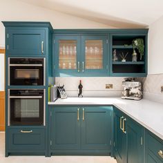 a kitchen with teal cabinets and white counter tops is seen in this image from the front view