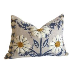 a blue and white pillow with daisies on it