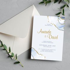 an elegant wedding card and envelope with greenery