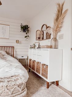 a bedroom with a bed, dresser and baskets on the sideboard in front of it