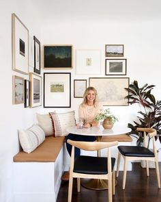 a woman sitting at a table in front of a bunch of pictures on the wall