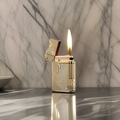 a gold colored lighter sitting on top of a marble counter next to a bowl and plate