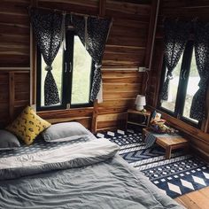 a bed in a room with wooden walls and windows