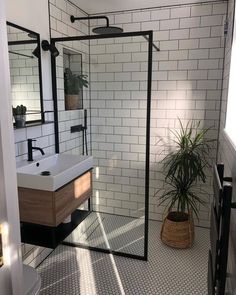 the bathroom is decorated in black and white tile with a shower stall, sink, and mirror