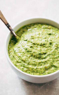 a white bowl filled with green sauce on top of a table