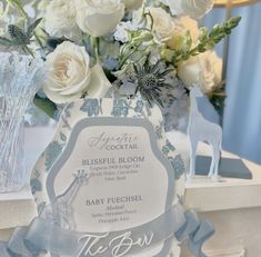 there is a vase with flowers in it and a baby shower sign on the table