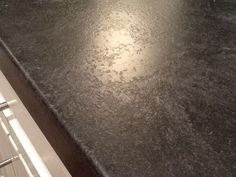 a kitchen counter top that is covered in dark colored granite, with the light reflecting on it