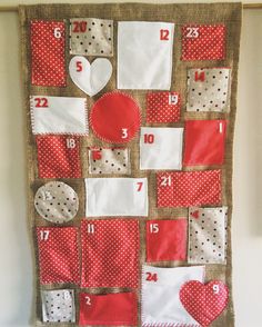 a red and white quilted wall hanging with numbers, hearts, and squares on it