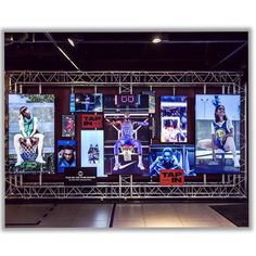 a large screen with pictures on it in a building at night, displaying various sports related items