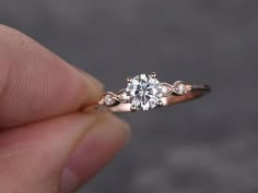 a hand holding a diamond ring in it's left hand, with the center stone on