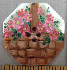 a painting of pink flowers in a basket on a wall next to a tape measure