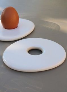 two plates with an egg sitting on top of each other, one white and one brown