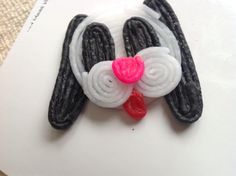 a close up of a dog brooch on a piece of paper with a pink heart in its mouth