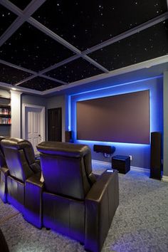 a home theater with blue lights and leather recliners in front of the screen