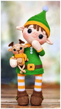 a small crocheted doll holding a baby deer in its arms and wearing a green knitted outfit