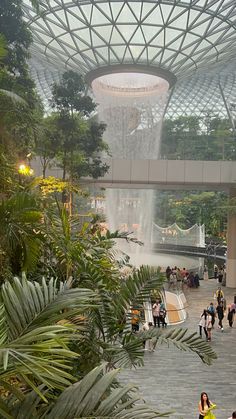 people are walking around in an indoor area with water spouting from the ceiling