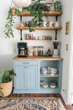 a kitchen with blue cabinets and shelves filled with pots, plants and coffee cups on top of them