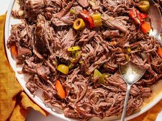 a white plate topped with shredded meat and vegetables next to a fork on top of a yellow towel