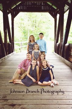 a group of people sitting on top of a wooden bridge