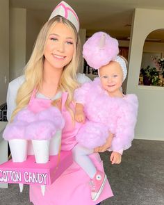 a woman holding a baby in a pink dress and cupcake costume while standing next to her