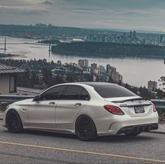 a white car parked on the side of a road next to a body of water