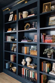 a bookshelf filled with lots of books and vases on top of it