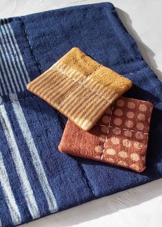 three towels folded on top of each other in different colors and patterns, sitting on a white surface