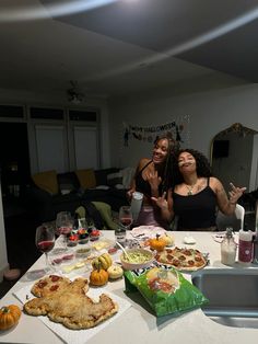 two women sitting at a table covered in food