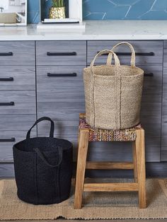 a basket sitting on top of a wooden chair next to a black trash can in a kitchen