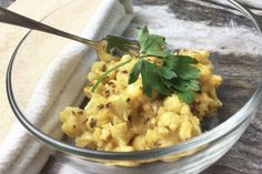 a glass bowl filled with scrambled eggs and garnished with parsley on top