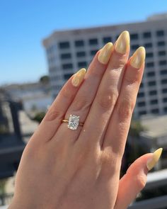 a woman's hand with yellow nail polish and a diamond ring on her finger