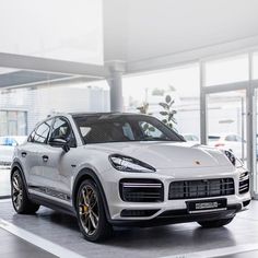 a white porsche cayen is parked in a showroom