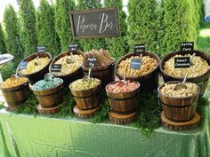 a table topped with wooden buckets filled with different types of popcorn and toppings