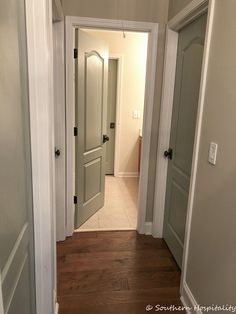 an empty hallway leading to another room with two doors on either side and one door open