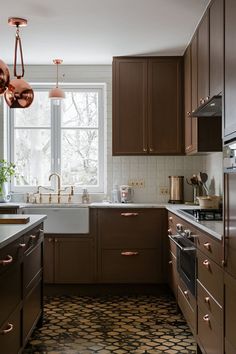 a kitchen with brown cabinets and white counter tops is pictured in this image, there are copper lights hanging from the ceiling