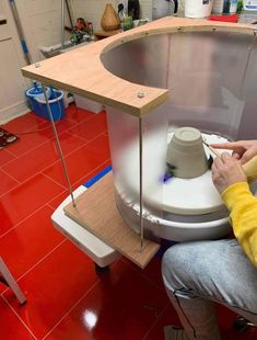 a woman is working on a toilet in a room with red tile flooring and walls