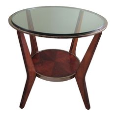 a round glass table with wooden legs and a shelf on the bottom that holds a wine bottle