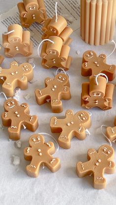 some little gingerbreads are sitting on a table next to an orange cup and candle