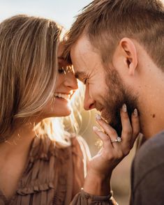 a man and woman standing close to each other with their faces touching foreheads as they look into each others eyes