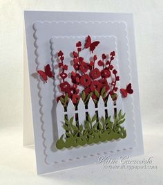 a white card with red flowers and green grass