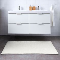 a white bathroom with two sinks and a rug