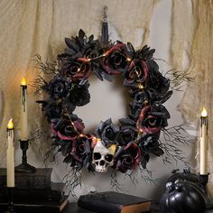 a wreath with skulls and roses is on the wall next to candles, books, and a book