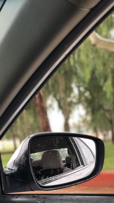 the rear view mirror of a car with trees in the background