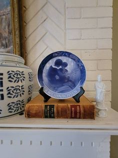 a blue and white plate sitting on top of a book next to an antique vase