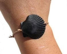 a woman's arm with a black shell bracelet on it, and a string wrapped around the wrist