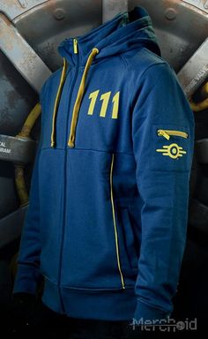 a man wearing a blue hoodie with the number 11 on it, standing in front of an industrial background